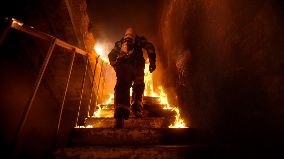 A stock image of a firefighter climbing stairs. 