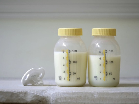 A stock image of two bottles containing milk and a pacifier. 