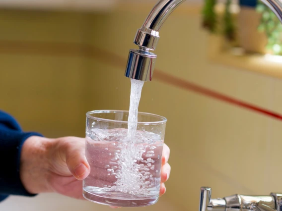 a glass of water being filled at a sink