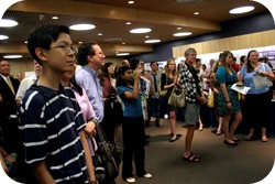 Students and trainees in a large room, watching the front of the room (not shown)