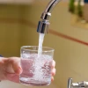 a glass of water being filled at a sink