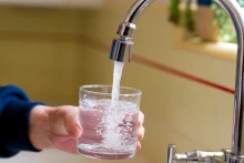 a glass of water being filled at a sink